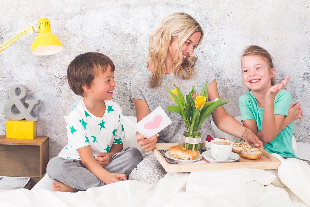 Mother and children enjoying breakfast in bed.
