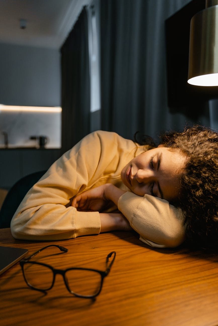 A person resting their head on a desk, appearing tired or contemplative.