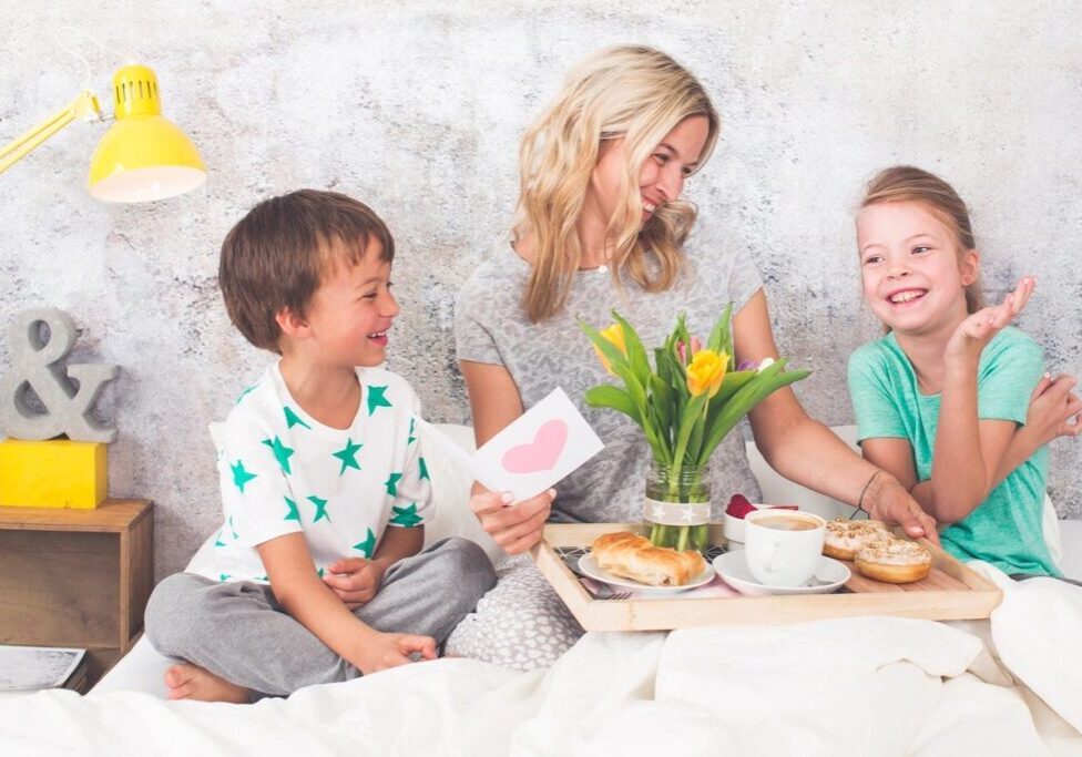 Mother and children enjoying breakfast in bed.